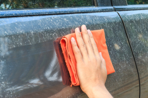 man wiping dirt off his car with a washcloth