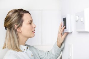 woman turning thermostat down