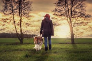 A woman walking her dog in a field