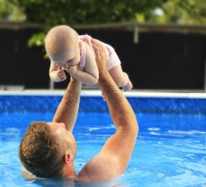 man playing with a baby in the swimming pool